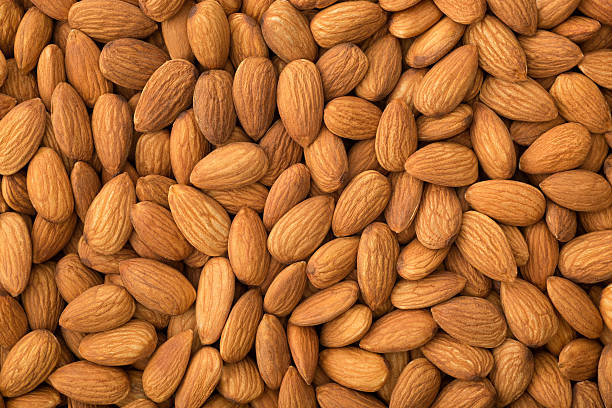 Raw almonds scattered on a rustic wooden surface