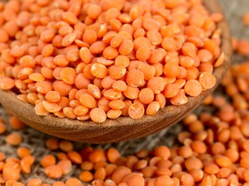 Red lentils in a white bowl on a wooden surface